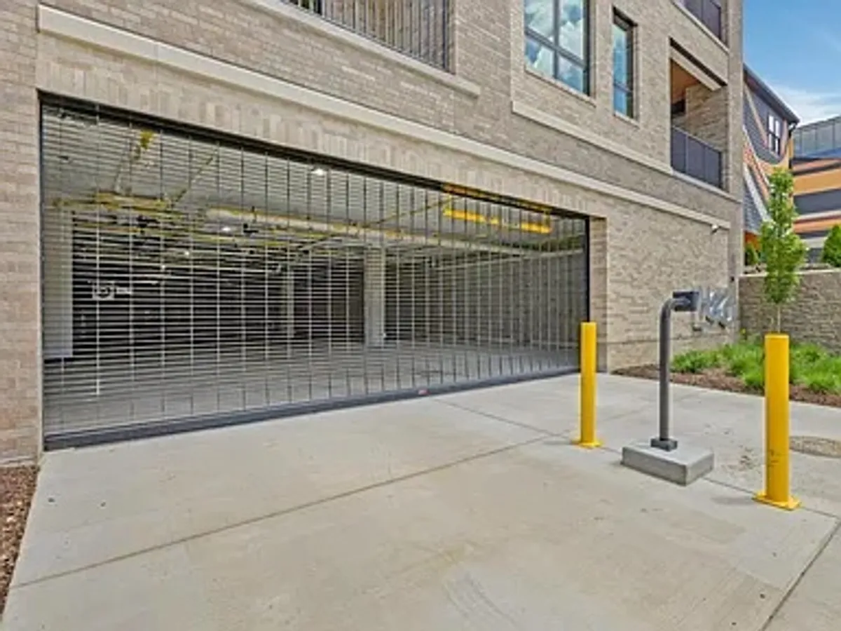 A secure, modern garage entrance with a security gate and yellow bollards. The area looks functional and safe, clearly designed to ensure peace of mind for residents and effortless access to parking.