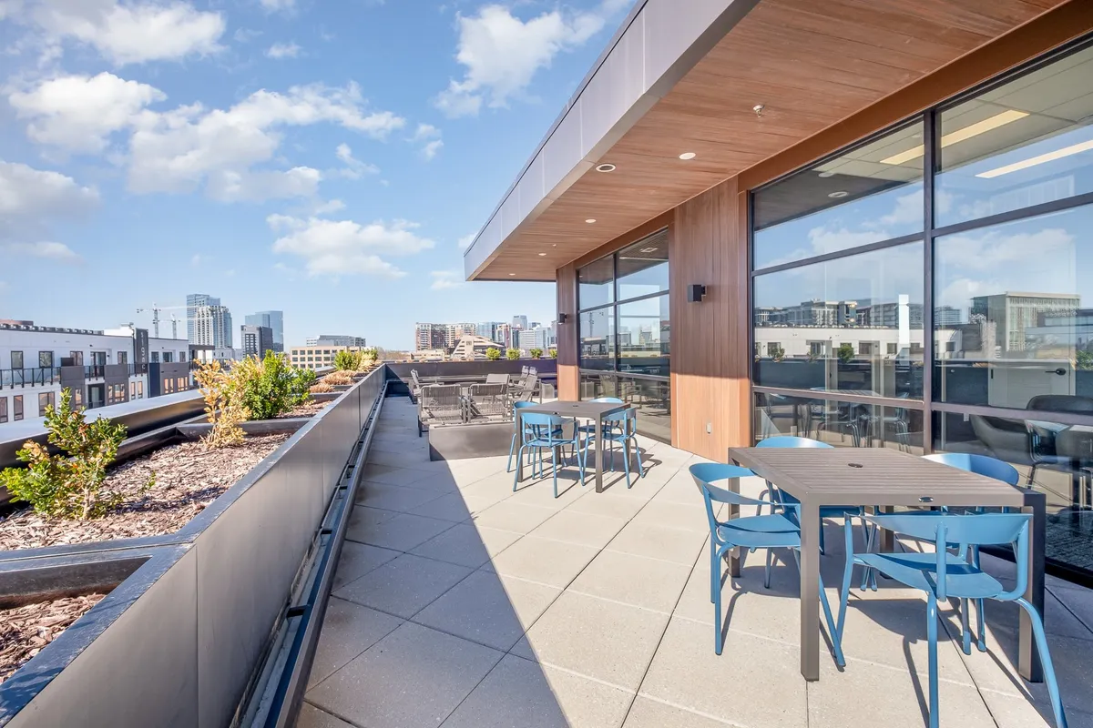 A spacious rooftop terrace featuring modern outdoor furniture, lush planters, and panoramic views of the city skyline. The space is designed for relaxation and socializing, with ample seating and a contemporary vibe ideal for sunset gatherings or cozy evenings under the stars.
